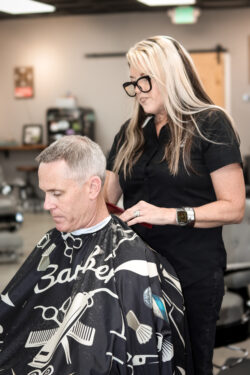 Female barber trimming a young client’s short haircut
